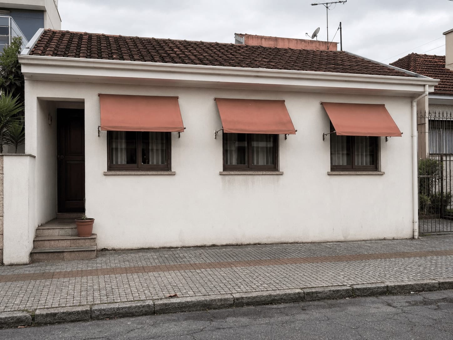 Fachada de casa em Curitiba com três toldos de lona sobre janelas
